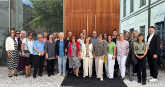 Viele Menschen stehen vor einer großen Holztür im Freien